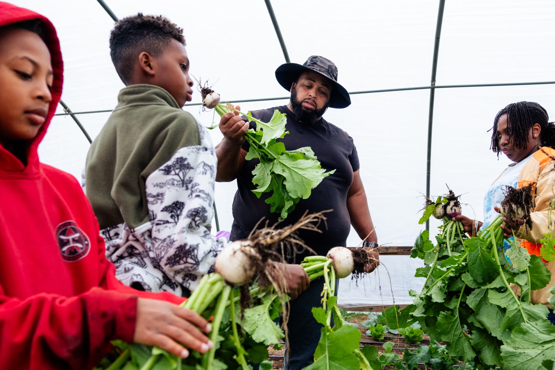 Jason Brown, former NFL player and owner of First Fruit Farms, inspects fresh turnips with his children to prepare a produce order for a customer.
Photograph: Cornell Watson/The Guardian