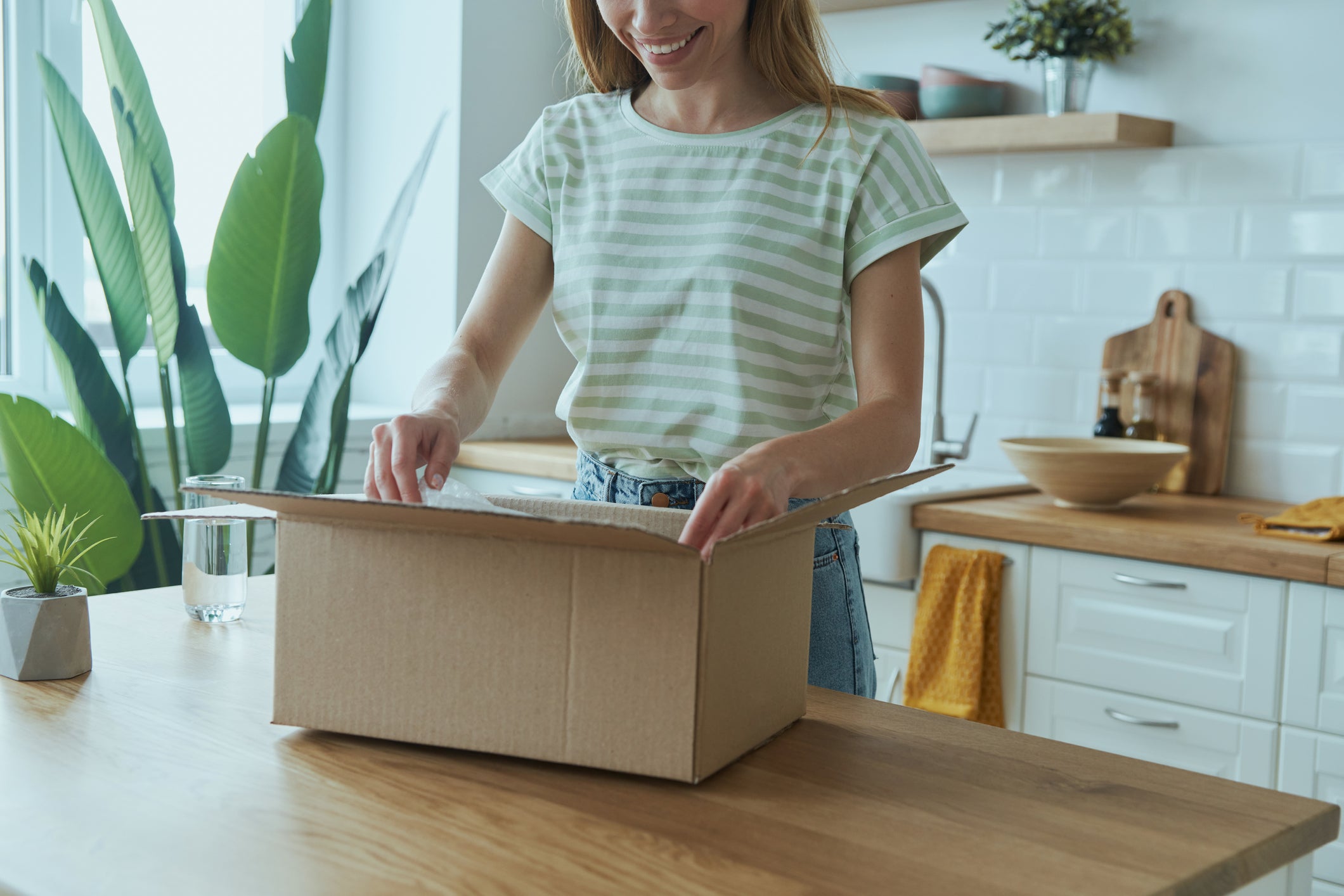 Customer opening a Greener Pastures Chicken home delivery box on a kitchen counter